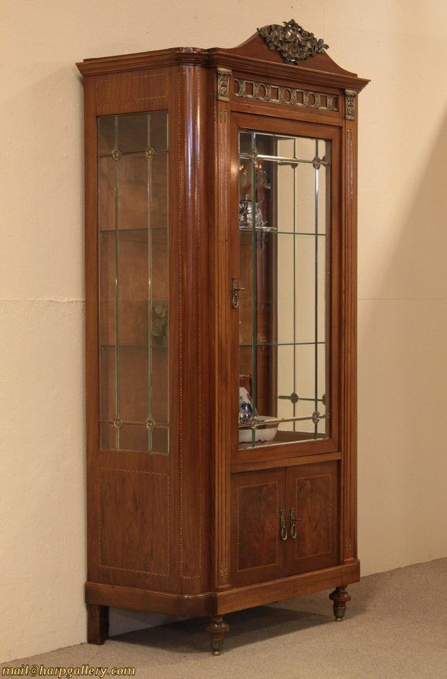 An elegant walnut china cabinet or curio display has beveled leaded